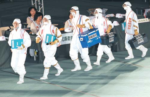 Agriculture officials and veterinarians, wearing protective suits and masks, perform a drill in a Hsinchuang gymnasium in Taipei County, yesterday./